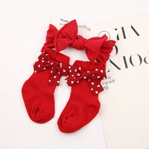 Detail of red baby headband with large bow and matching heart socks on a magazine