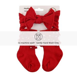Detail of red baby bow headband and heart pattern socks set on white display card