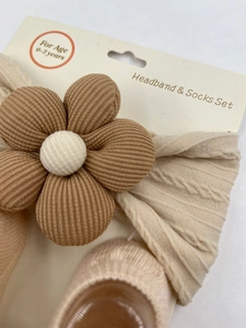 Detailopname van beige baby haarband met bruine corduroy bloem en bijpassende sokken set