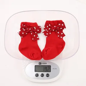 Detail view of red baby socks with heart bows on a digital scale weighing 19.2g