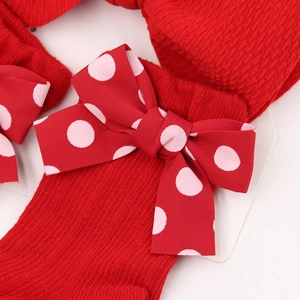 Close-up of red polka dot bow and ribbed knit fabric on baby holiday accessory set