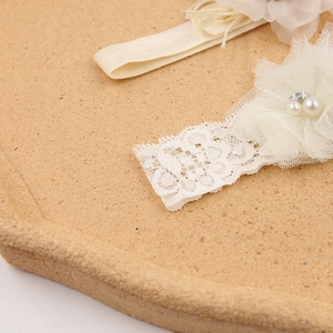 Primo piano della fascia per neonati in pizzo crema con fiori in tulle e perle