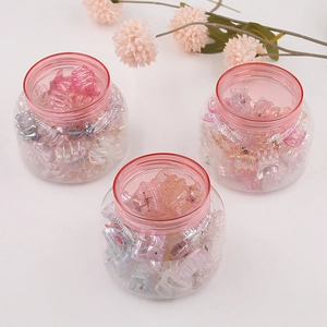 Macro shot of three round jars filled with colorful transparent mini hair claw clips