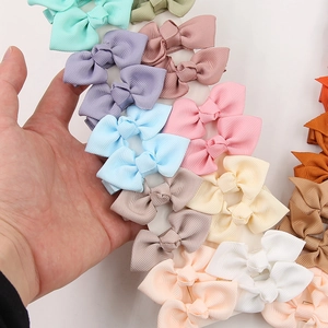 Detail showing various colors of ribbed grosgrain ribbon bow hair clips on a display card