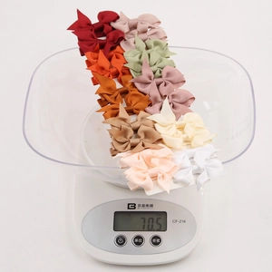 Detailed view of colorful grosgrain ribbon hair bows weighing 70.5g on a digital scale