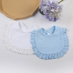 Detail of white and light blue cotton muslin bibs with ruffles and snap buttons