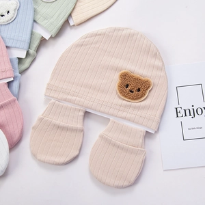 Detail of organic cotton newborn baby beanie and mittens set with cute bear patch