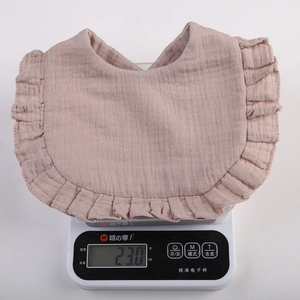 Lightweight 23g cotton gauze baby bib with ruffle edges shown on a precision scale
