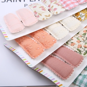 Détail de barrettes pour enfants en tissu à motifs floraux et à carreaux sur carte