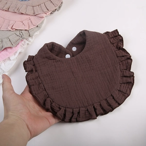 Detail of ruffled cotton baby bibs featuring soft gauze fabric and snap button closure
