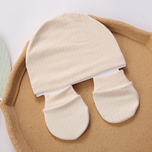 Detail of baby organic cotton ribbed beanie and anti-scratch mittens in beige tray