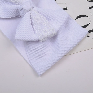 Détail du bandeau bébé blanc en maille gaufrée avec grand nœud orné de dentelle fine