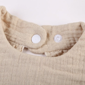 Detailed macro view of the breathable beige cotton crepe fabric and white snap closure button