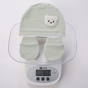 Digital scale showing newborn baby bear hat and glove set weight of 35.5g in light green