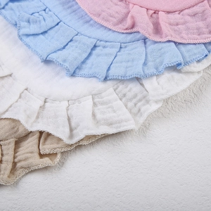 Detail of soft cotton muslin baby bibs with ruffle edges in pastel colors