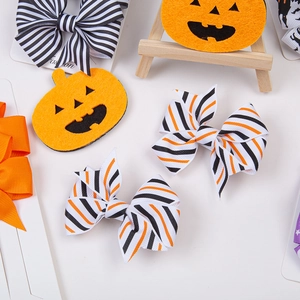 Dettaglio di fermagli per capelli di Halloween con fiocchi a righe e zucca in feltro