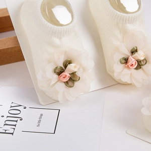Detalle de calcetín de punto para bebé con flores de gasa y rosas artesanales