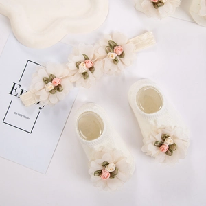 Detalle del set de diadema y calcetines para bebé en crema con flores de gasa finas