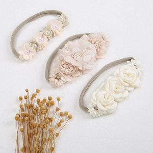 Detailed close-up of 3 handmade floral baby headbands with lace, satin, and pearls