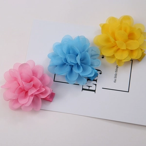 Dettaglio dei fermagli per capelli a fiori in chiffon nei colori rosa, azzurro e giallo