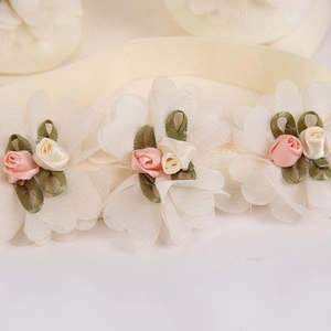 Detalle de diadema para bebé con flores de organza blancas y rosas de tela rosa