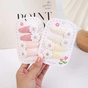 Détail de quatre barrettes en tissu faites main avec petites marguerites
