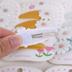Détail du clip métallique et de la texture de dentelle marguerite blanche sur la pince