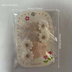 Détail de quatre barrettes à fleurs de marguerite brodées sur une carte de présentation