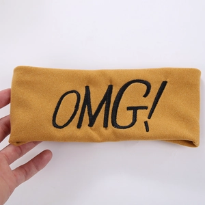 Detail showing ginger yellow headband with black OMG! embroidery and elastic knit texture