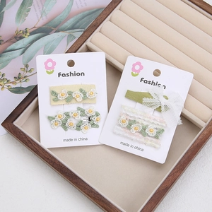 Détail de barrettes à fleurs brodées à la main avec nœuds en dentelle sur support bois