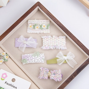 Détail de barrettes à fleurs faites main avec broderies et nœuds en maille douce