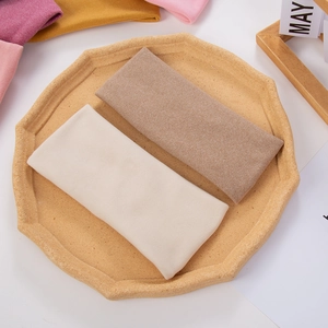 Detailed texture of assorted soft knitted headbands displayed in a rustic wooden tray