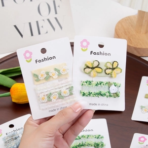 Détail de barrettes à fleurs brodées à la française et nœuds sur cartes