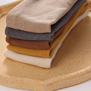 Macro detail of elastic knitted headbands in Morandi colors on a cork tray