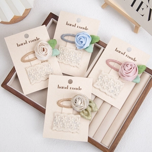 Detail of four floral lace BB hair clips with 3D satin roses on display cards