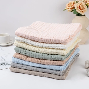 Close-up of stacked six-layer cotton gauze baby towels in multiple soft colors and textures