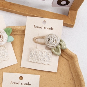 Detail of handmade champagne satin rose clip and white lace embroidery on card