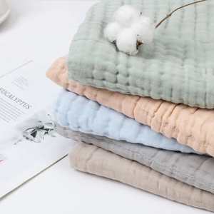 Detailed view of layered 6-layer muslin cotton baby towels in assorted pastel colors