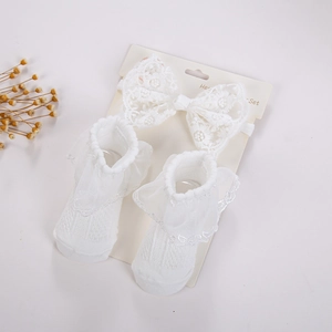 Detailansicht von Baby-Stirnband mit großer Schleife und passenden Söckchen mit Spitze