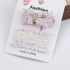 Détail de barrettes à cheveux en tweed rose et bleu avec nœud sur carte de présentation