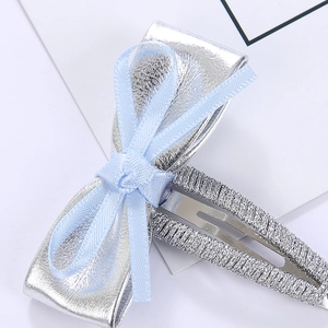 Vue macro d'une barrette à nœud argenté avec ruban bleu clair et pince BB tissée main