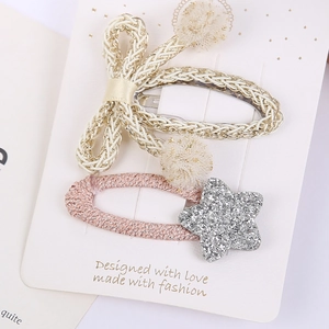 Détail de la pince à cheveux nœud tissé avec pompons et clip étoile argentée brillante