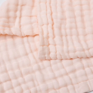 Close-up of baby pink 6-layer muslin gauze fabric with soft bubble texture and neat edges
