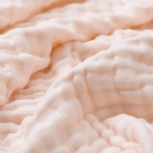 Macro detail of soft six-layer bamboo cotton muslin fabric texture in light pink