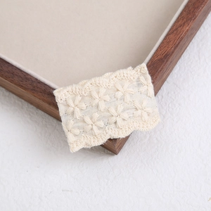 Close-up of cream white floral lace embroidery details on a cute fabric hair clip