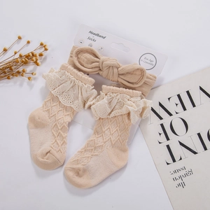 Close-up of beige infant waffle knit socks with lace trim and matching bow headband set