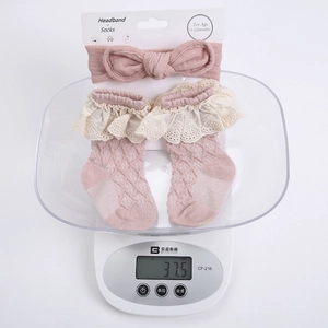 Detailed view of pink knitted baby headband and lace socks set on a display card