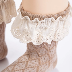 Detailed macro view of baby socks featuring double-layer lace ruffles and knit texture