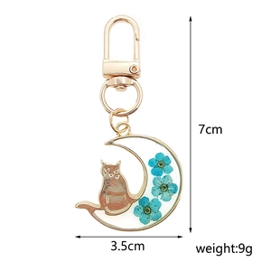 Detailed size view of moon cat keychain with blue dried flowers and resin pendant