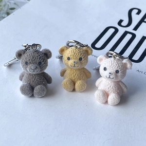 Trois porte-clés ours floqués en résine gris, jaune et rose avec fermoirs mousquetons en métal